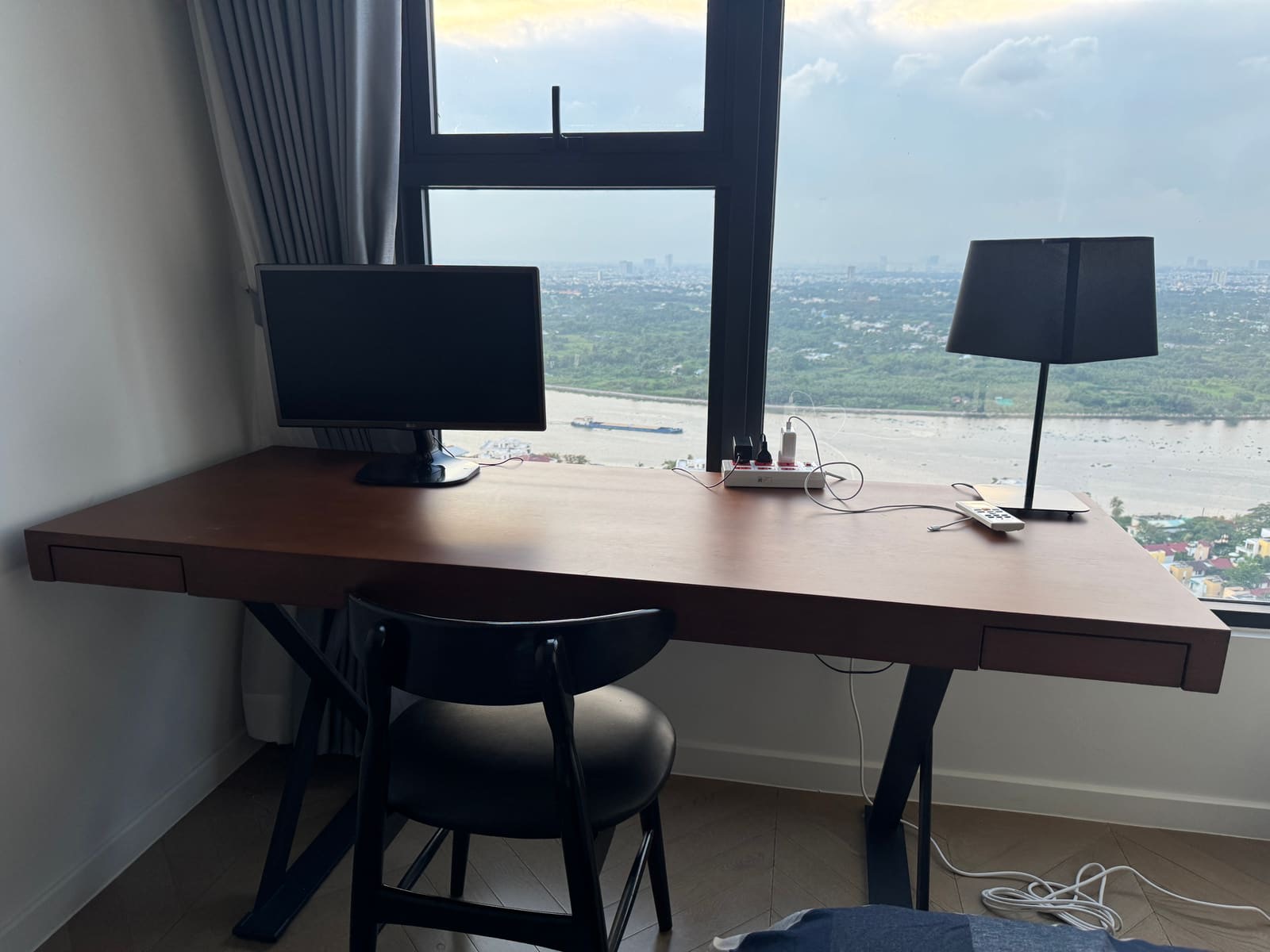 A work desk with an external monitor and the Saigon river beyond the window