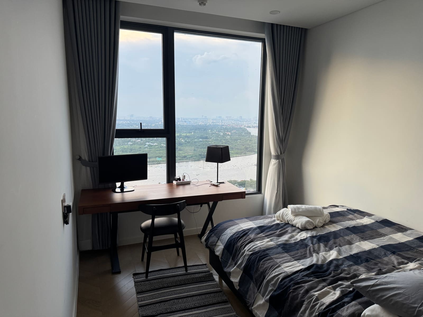 A bedroom on a high floor with a desk and the river below