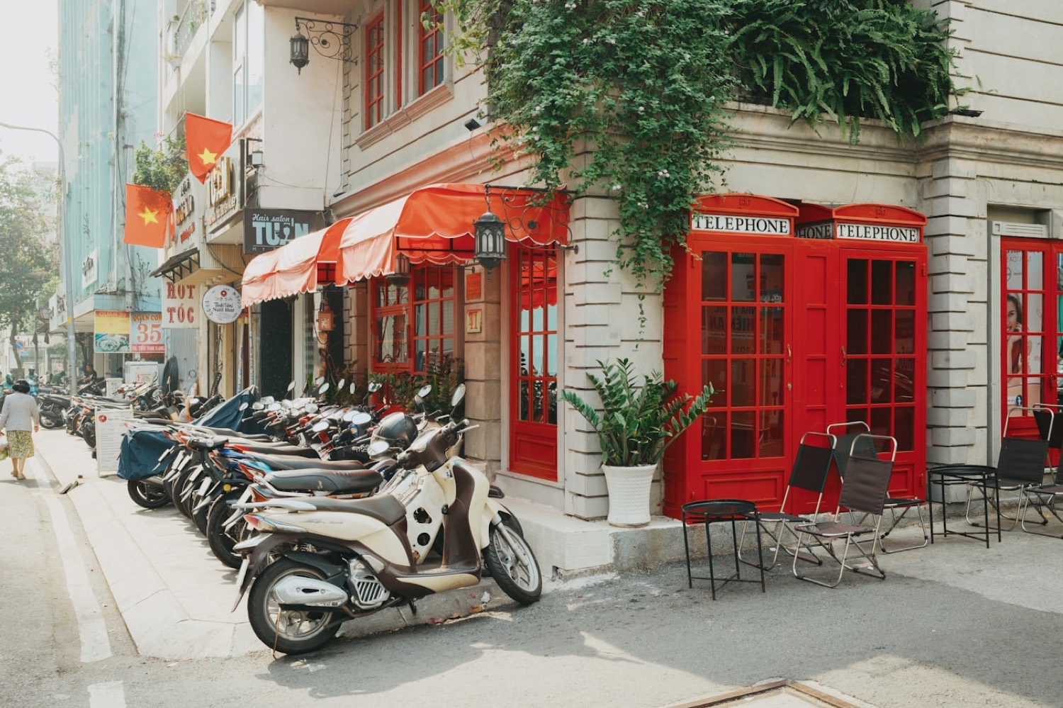 A leafy street-corner cafe in Saigon, motorbikes parked along the kerb