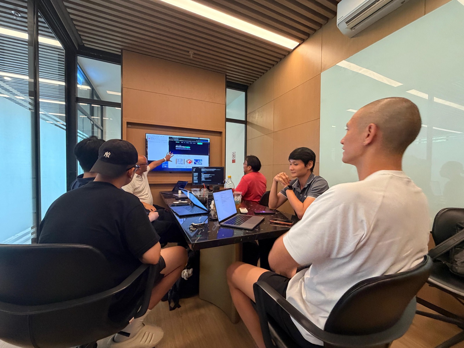 The full group gathered around a screen, working through a build together